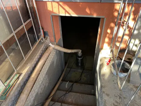 A pump hose running down the steps into a flooded cellar