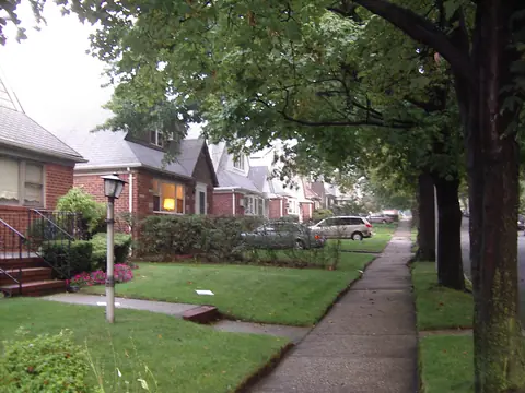 A quiet Bayside street with brick houses, lawns and tall trees
