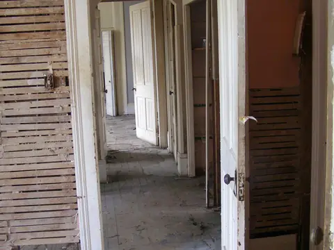 A gutted hallway in a flood-damaged house, with doors open into stripped rooms