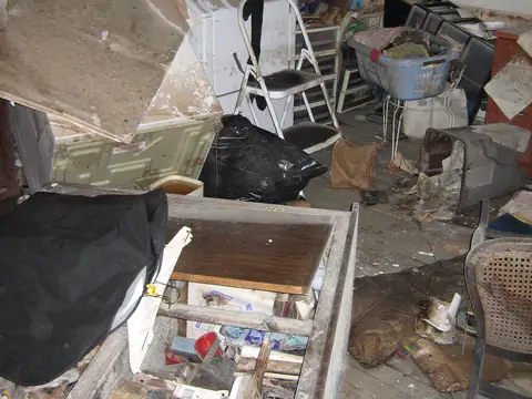 A flooded utility room with ruined belongings and mold on the walls