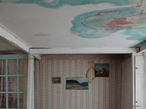 Water stains spreading across the ceiling of a small bedroom