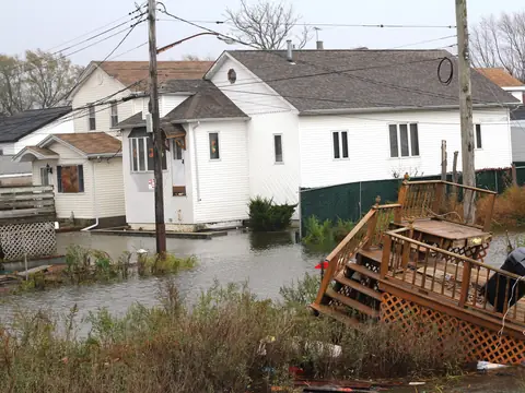 Floodwater around white houses in Howard Beach, Queens, with a wooden deck torn loose after Hurricane Sandy