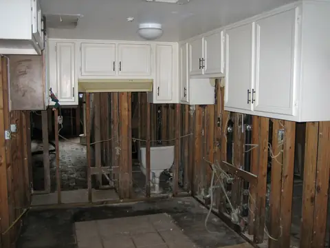A flooded kitchen with the lower walls and flooring torn out below the cabinets