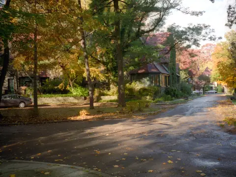 A curving street of houses under autumn trees in Forest Hills Gardens, Queens