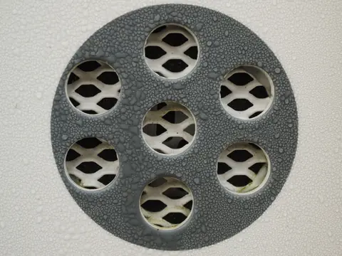 A round floor drain cover beaded with water