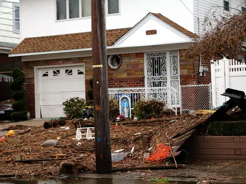 Storm debris piled in front of a brick house in Howard Beach, Queens, after Hurricane Sandy