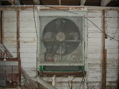 A large box fan set in an old basement window