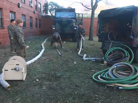 Pump hoses laid out across a yard toward apartment buildings after Hurricane Sandy