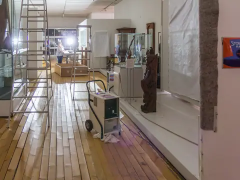 A dehumidifier on wheels drying a hallway with a water-damaged wood floor