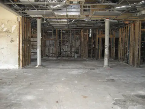A gutted ground floor with the walls opened to the studs and a bare concrete floor