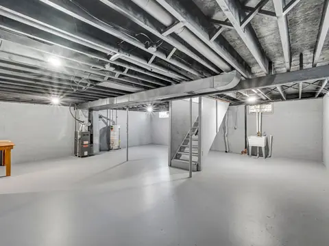 A basement with a painted concrete floor, a water heater and a furnace