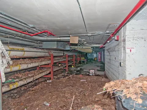Mud and debris across the floor of a basement corridor after floodwater drained away