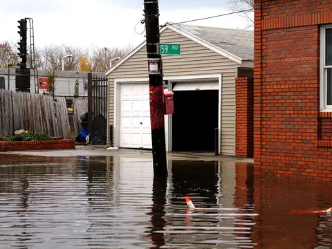 Floodwater standing in a Howard Beach street outside a garage and a brick house after Hurricane Sandy
